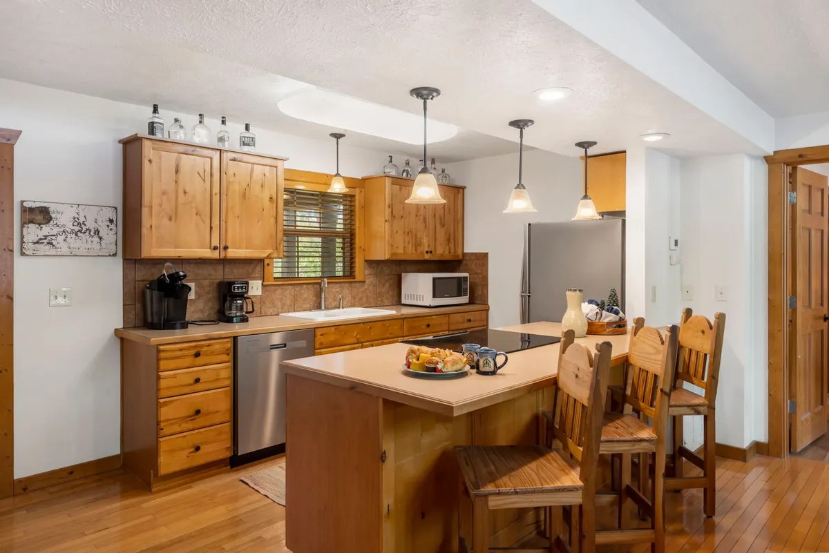 A cozy kitchen scene with a large island, wooden cabinetry, appliances, and bar stools inviting guests to linger. The setup encourages both cooking together and casual dining, with the island serving as a hub for snacks, drinks, or conversation.