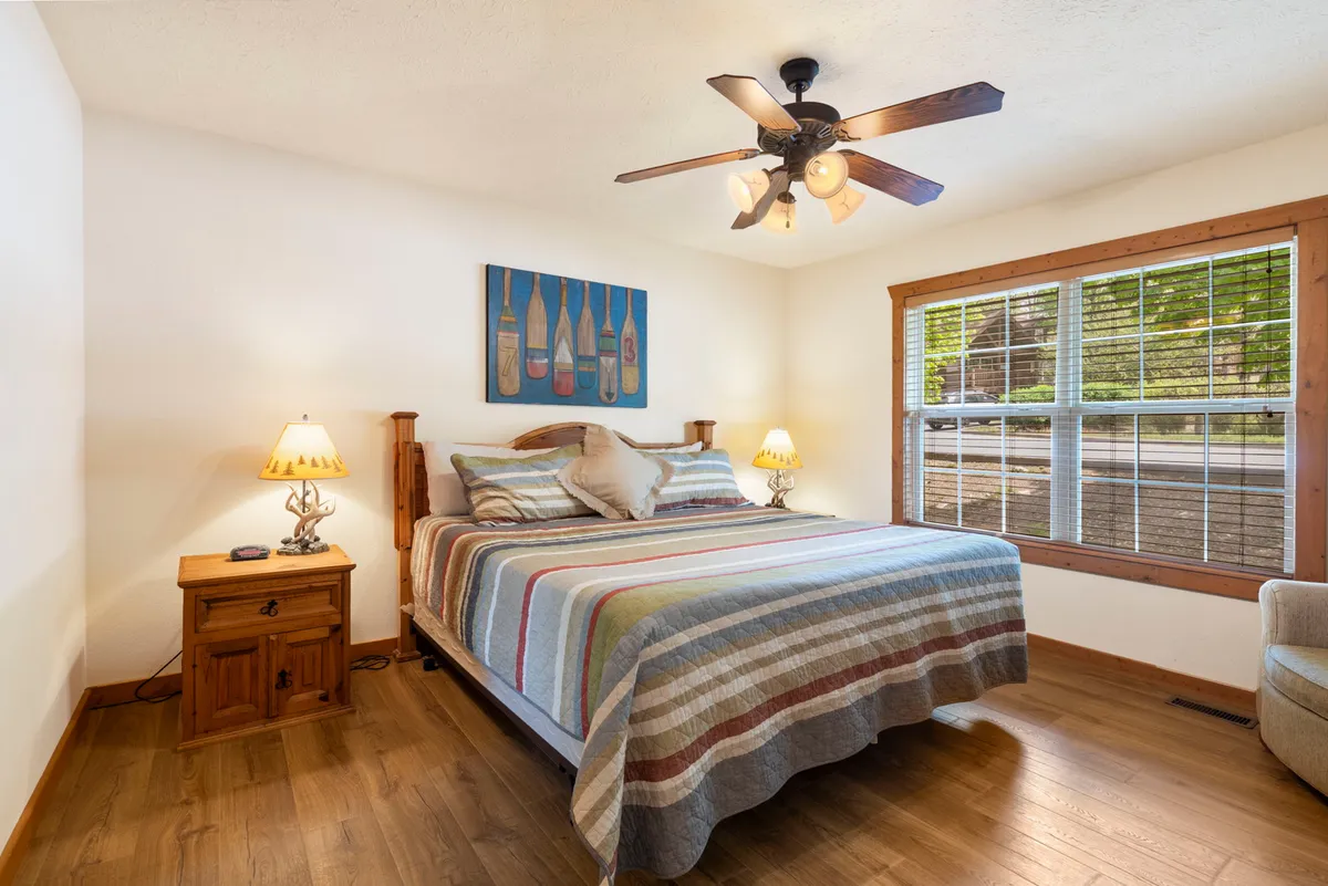 A cozy bedroom highlighted by a large king bed, tasteful artwork, bedside lamps, and a window allowing in natural light. The room's tranquil ambiance invites relaxation and a good night's rest.