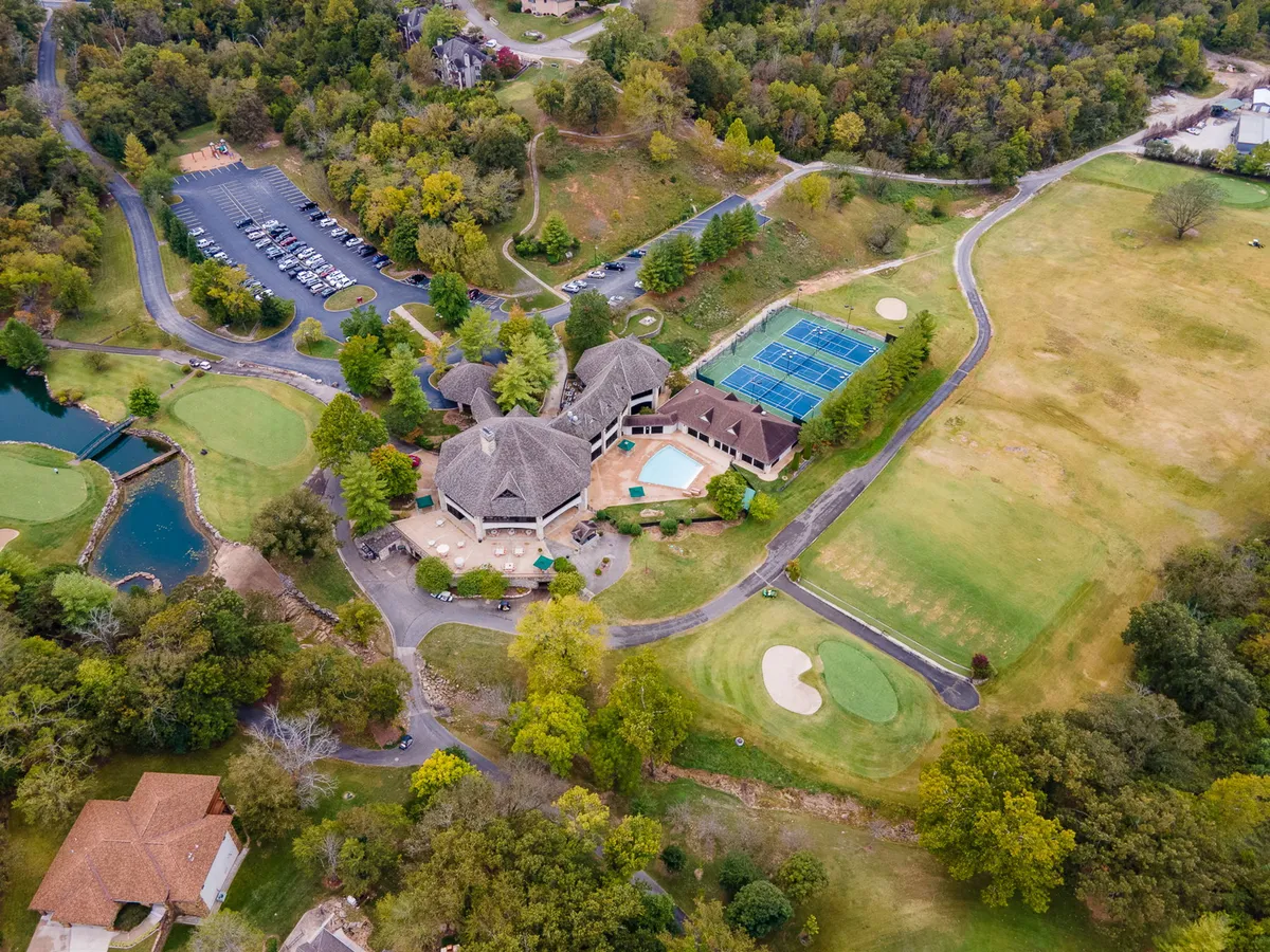 An aerial exterior view featuring the championship golf course, tennis courts, a swimming pool, and the resort clubhouse, all set amidst manicured landscaping. The image exudes a sense of space and variety in recreational amenities available at the resort.