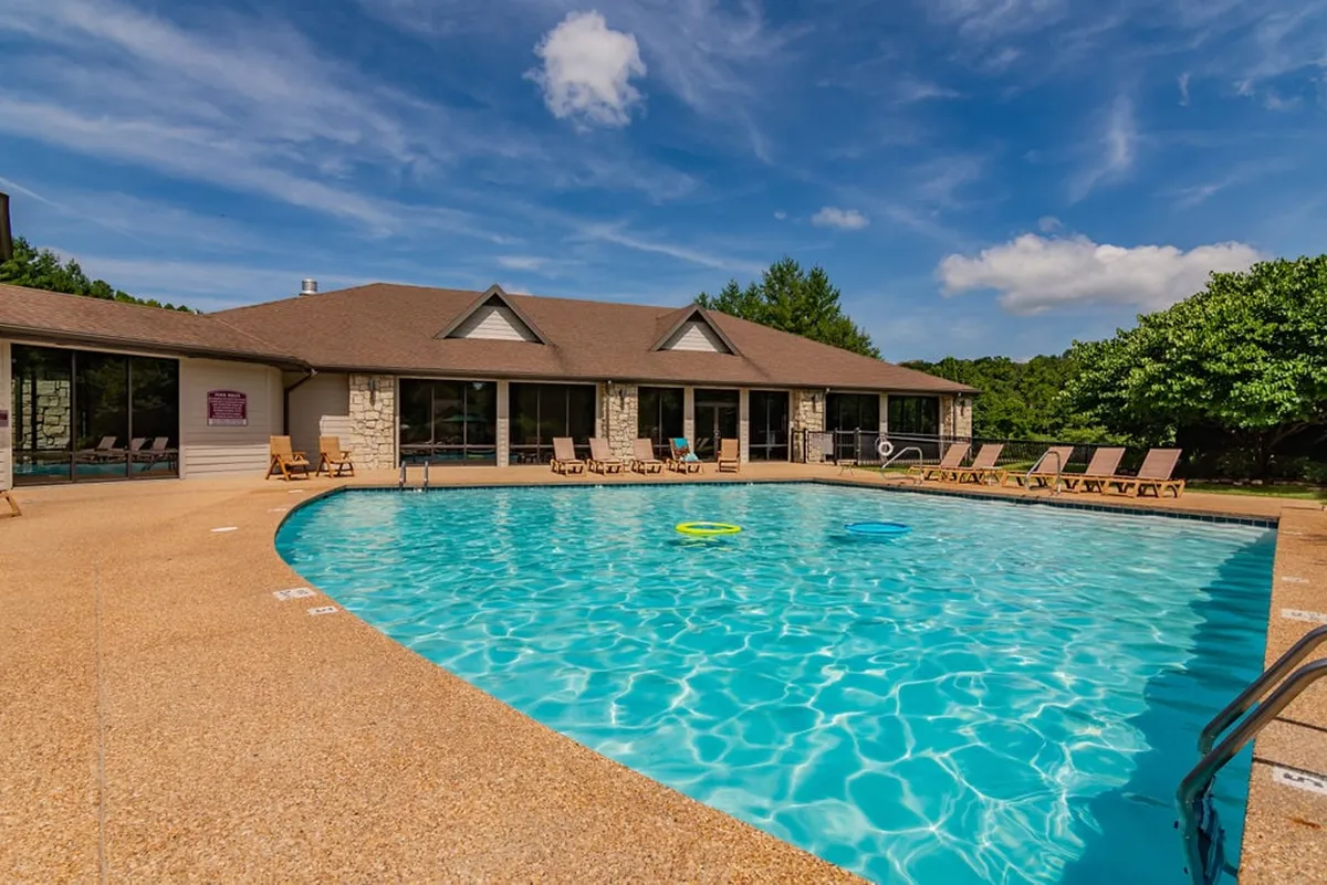 This exterior image showcases a sparkling swimming pool surrounded by lounge chairs and lush greenery, with the resort's building facade visible in the background. The scene captures a relaxed, social atmosphere perfect for cooling off or unwinding.