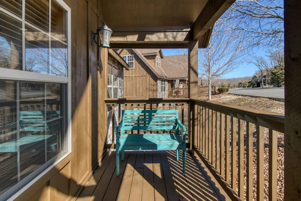 An exterior porch with a turquoise bench, wooden railing, and lantern light fixture, set against a tranquil backdrop. The scene invites morning coffee, storytelling, or simply soaking in the peaceful vibe before or after a busy day out.