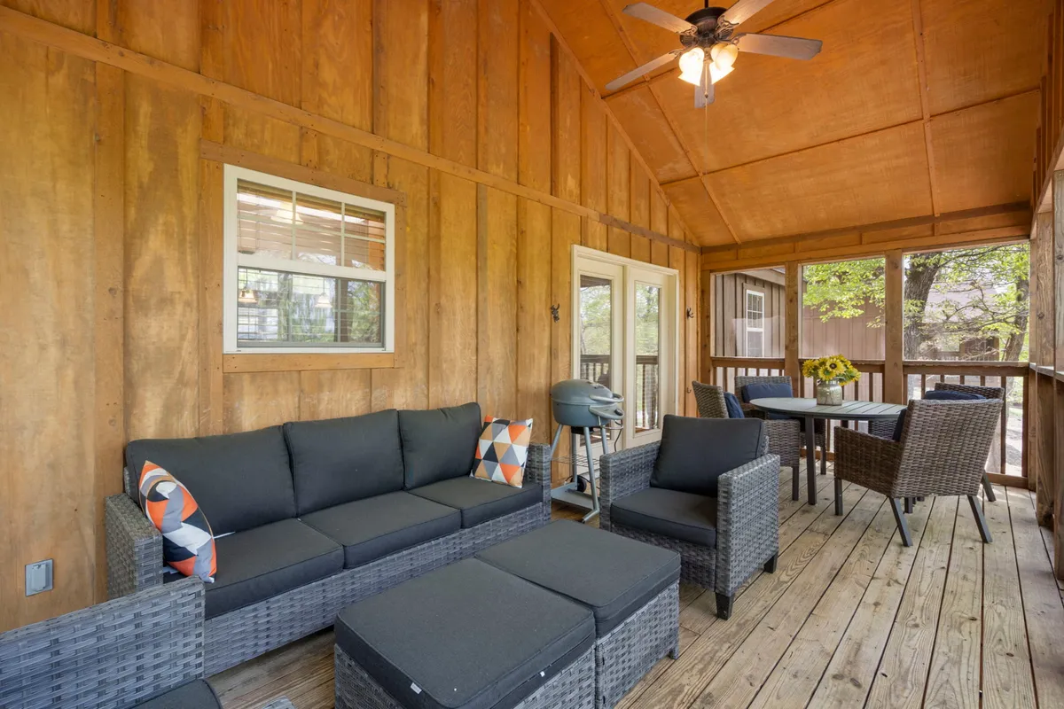 A screened-in porch scene with a comfortable seating area, dining table, and grill. The space feels airy and welcoming—perfect for al fresco meals with tranquil views, as described in the section.