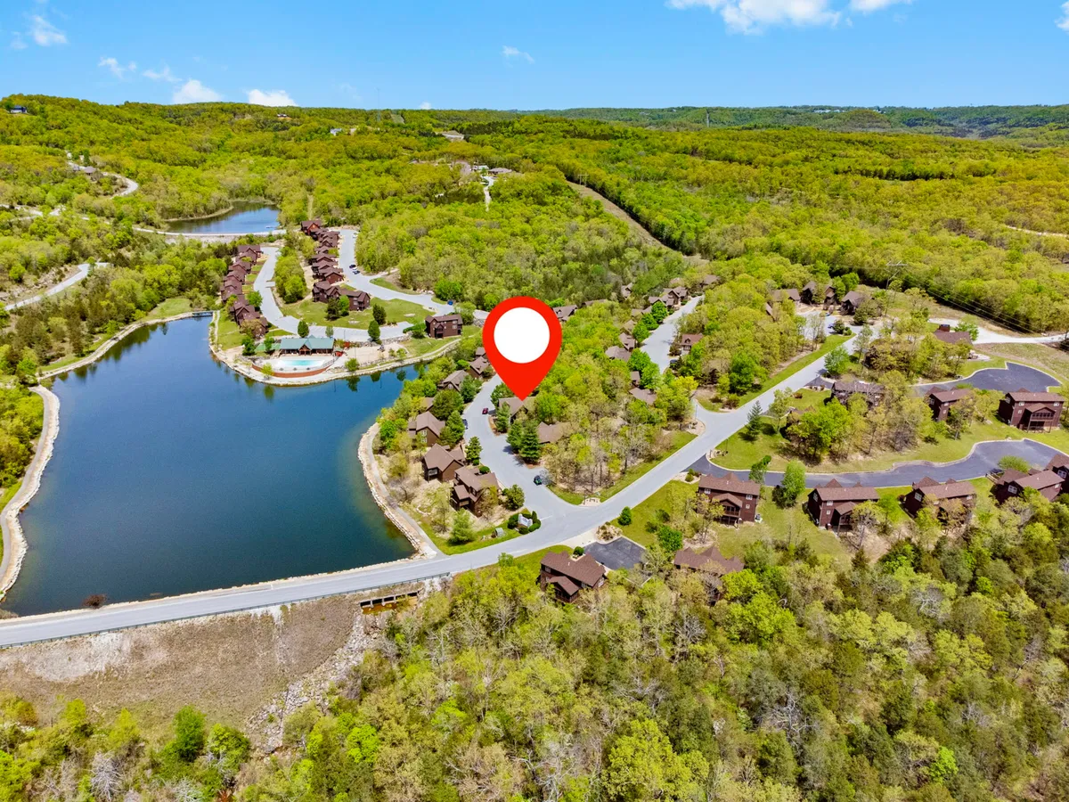 A tranquil lakeside scene with lush greenery, wooden cabins nestled along the shore, and winding paths leading through the landscape. The lake is calm and inviting, perfect for fishing, boating, or simply enjoying a peaceful walk. The overall mood is serene and ideal for family relaxation or multigenerational outings.
